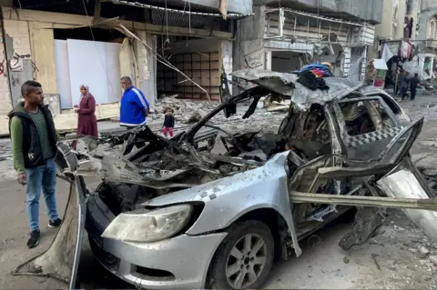 AFP Onlookers check the car in which three sons of Hamas leader Ismail Haniyeh were reportedly killed in an Israeli air strike in al-Shati camp, west of Gaza City on 10 April 2024