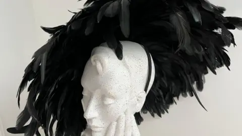 An oval shape of black feathers with a head band to hold it in place