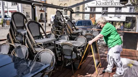 EPA Chairs and tables are prepared for outdoor dining at a restaurant in Aalborg, Denmark