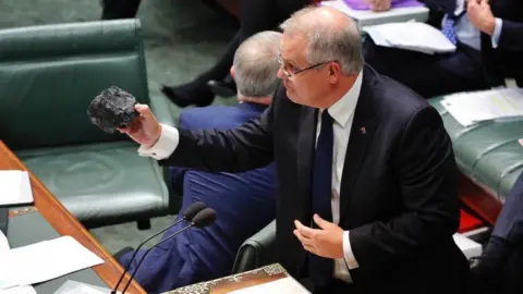 ABC News Prime Minister Scott Morrison holds a lump of coal while giving a speech in parliament.