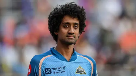 R Sai Kishore standing on the pitch wearing a jersey for Gujarat Titans during a match in 2025