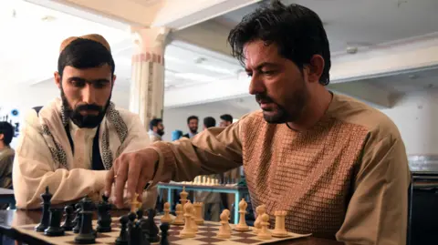 A stock image of a man playing chess in a tournament in Kandahar in June 2022