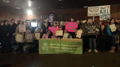 A group of protesters carrying banners against the proposed closures outside a previous council meeting.