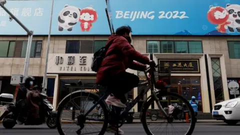 Reuters A person cycles past a Beijing 2022 sign