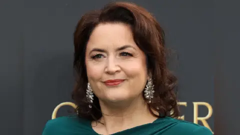 Getty Images Ruth Jones in a green dress looking at the camera. She has silver dangly earrings in and her dark hair frames her face. 