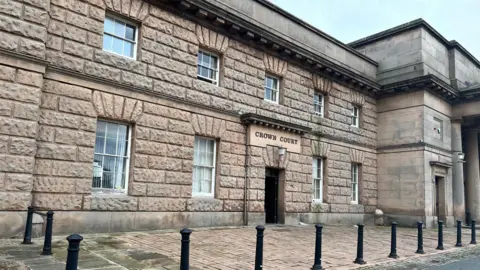 The frontage of Chester Crown Court, a light-coloured building with the words 'crown court' above the entrance