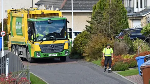Getty Images A refuse lorry and worker in a leafy street in Fife.