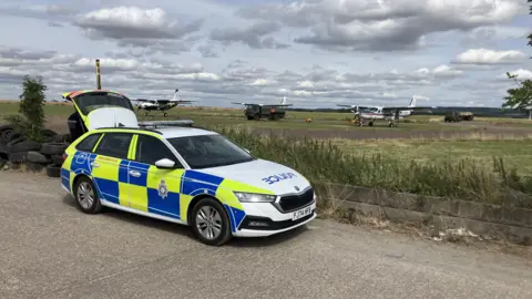 BBC A police car parked near an airfield in Nottinghamshire