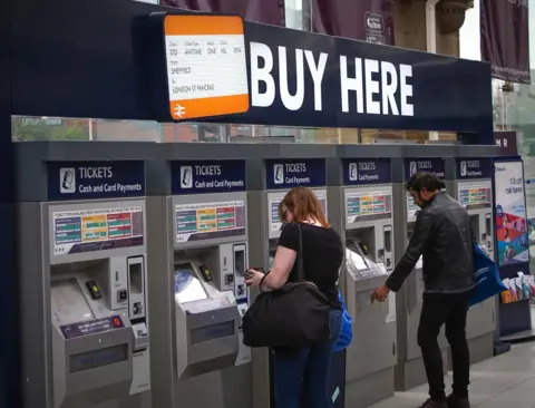 Getty Images People buy train tickets at a machine