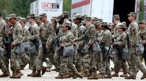 Tribune News Service via Getty Images A group of the Texas National Guard, wearing full green and brown camouflage military fatigue uniforms, assemble at the Army Reserve Training Center in the southwest suburb of Chicago.  