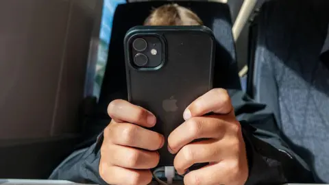 A persons face is obscured as they use a phone on a train. 