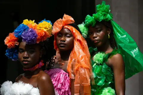 EMMANUEL ADEGBOYE / EPA Models wear outfits made of plastic bags in bright colours.