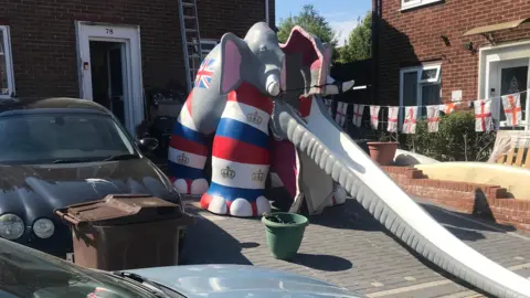 A multi-coloured elephant slide in a driveway of someone's house.