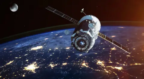 A satellite up in space. The earth can be seen in the image, as can the moon.