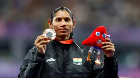 Reuters Paris 2024 Paralympics - Athletics - Women's 400m - T20 Medal Ceremony - Stade de France, Saint-Denis, France - September 3, 2024 Bronze medallist Deepthi Jeevanji of India celebrates on the podium