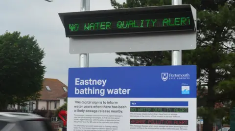 Portsmouth City Council A close-up picture of the electronic sign, which says 'no water quality alert' in green writing, and the sign below it titled 'Eastney bathing water' which explains how the digital display works.