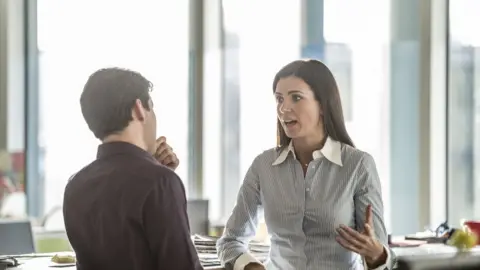 Getty Images Man and woman talking in an office