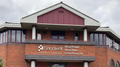 A red brick council building with a sign that reads 'Sandwell'