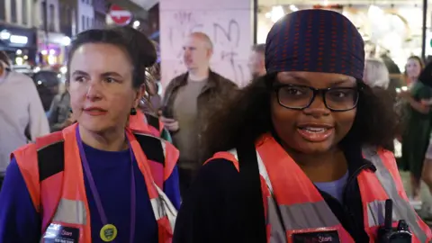 LDRS Rebecca Damm (left) and Emmanuella Fadire wearing their pink high vis Night Stars vests while patrolling Soho