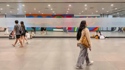 Kelly Ng/BBC People walking through the underground passage connecting a train station to Gardens by the Bay