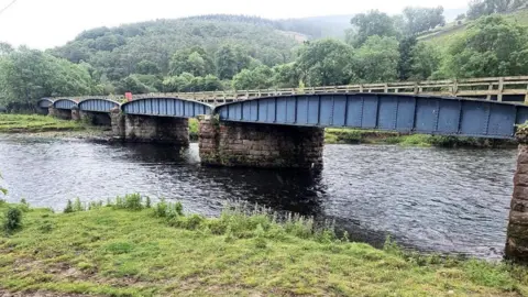 Oliver Dixon A viaduct in the Borders across water with rolling hills in the background