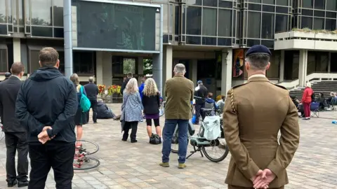 People in Guildhall Square in Portsmouth watching a big screen showing the Queen's funeral