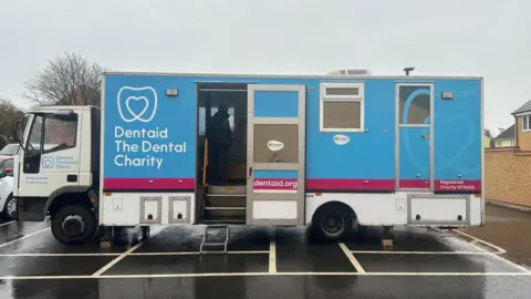 AnnaLouise Walter/BBC Blue and white lorry with "Dentaid" sign