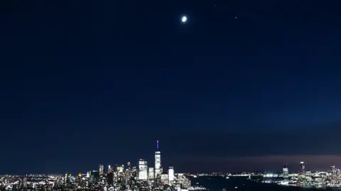 Getty Images The moon, Saturn and Jupiter form a triangle as they rise over lower Manhattan and One World Trade Center