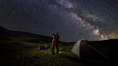 Getty Images A father and a child, camping, admiring the starry night sky