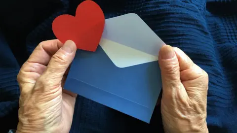 Getty Images Elderly person holding a Valentine's card