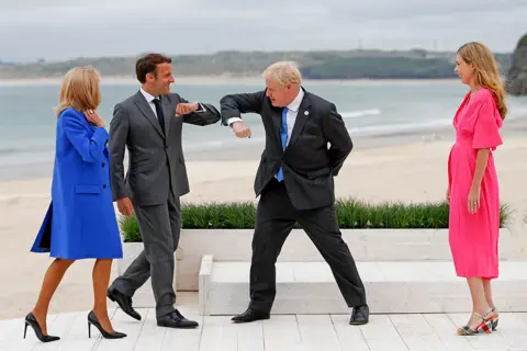 EPA Prime Minister Boris Johnson greet France's President Emmanuel Macron with an elbow bump as their spouses look on in Cornwall, during the G7 summit