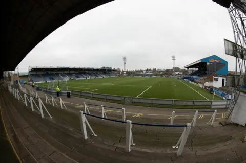 SNS A view of Palmerston Park in Dumfries with terraces in the foreground and a pitch and two stands with another terrace in the distance