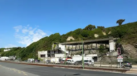The Summerland site, which has the remains of of a demolished building on it and a few parked cars.