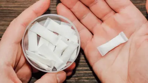 Getty Images A small tub of nicotine puches with one in a person's hand