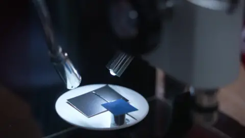 Close-up of a microscope and torch on a piece of black card with a needle on it