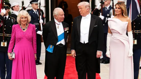 Queen Camilla, King Charles III, U.S. President Donald Trump, and First Lady Melania Trump pose at the base of the Grand Staircase during an official state dinner hosted by the President and First Lady at The White House on day two of the State Visit