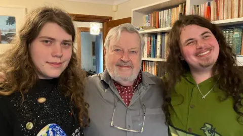 Three men with their arms around each other looking into the camera