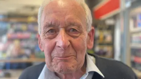 Nick Briggs from Pittvale Service Station an elderly man looking at the camera from his shop.