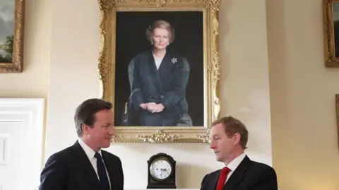 Former Tory Prime Minister David Cameron and Irish Taoiseach Enda Kenny stand in front of a portrait of Margaret Thatcher