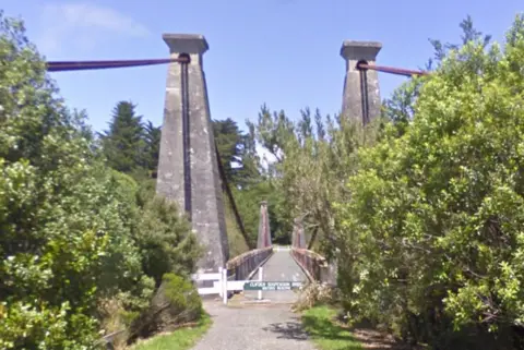 Google A stone suspension bridge flanked by trees