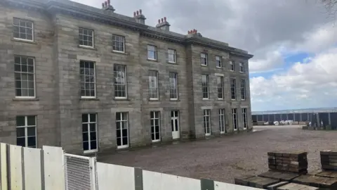 Photograph of the exterior of Haigh Hall in Wigan. The image shows the wooden boarding which is closed-off to the public.