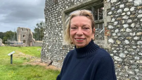 Andrew Turner/BBC Jo Brannigan stands next to the wool factory, part of Baconsthorpe Castle