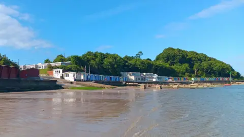 Sheila SATURDAY - Brightly coloured beachhuts next to a sunny beach at Totland Bay on the Isle of Wight