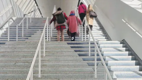 Thirty-two steps leading up to a shopping centre, four people are on the stairs.