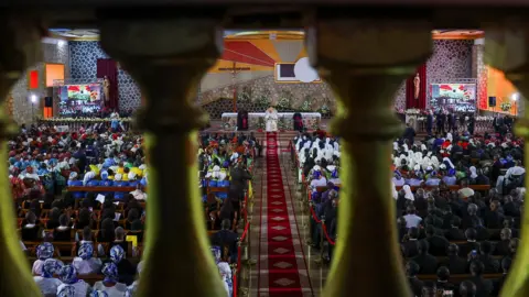 Reuters The Pope, bishops and congregation seen through a railing in a cathedral in Bamenda