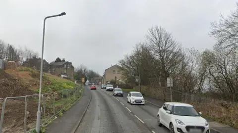 Park Lane in Keighley, a steep road with queuing traffic heading down the hill. 