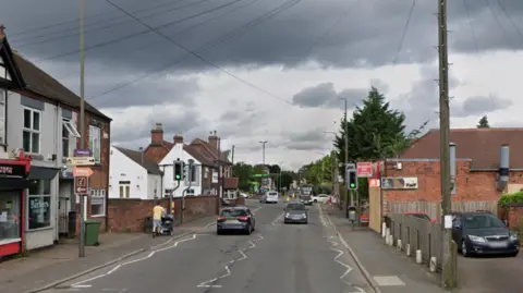 A long street through a town with cars on it