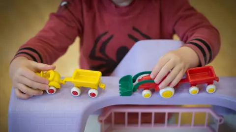 Stock image of a child - whose face cannot be scene - playing with toys.
