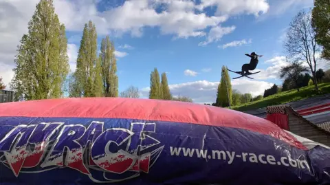 Gloucester Ski & Snowboard Centre A skier mid-jump coming off the ramp with a large crash mat closest to the camera.