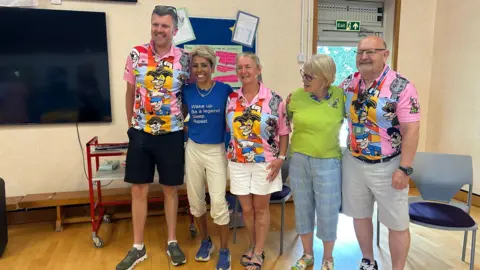 Former Olympian Dame Kelly Holmes on a visit to Le Rondin School on Guernsey. She is wearing a blue T-shirt which reads 'Wake up. Be a legend. Sleep. Repeat'. With her are staff from the school.